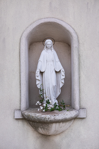 woman sculpture with rose basket made of marble in a park or cemetery, copy space