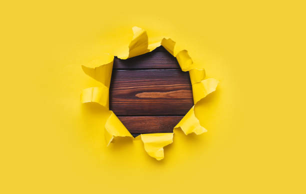 torn hole in yellow paper with black empty background. copy space, mockup. place for text or logo. - bullet hole exploding hole tearing stock-fotos und bilder