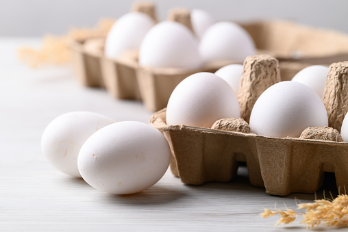Organic white leghorn egg from free range farm in paper tray on white table