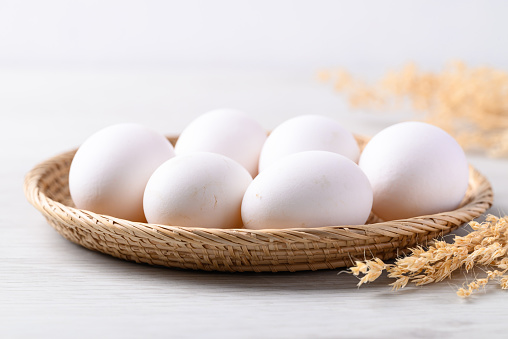 Organic white leghorn egg from free range farm in natural basket on white table