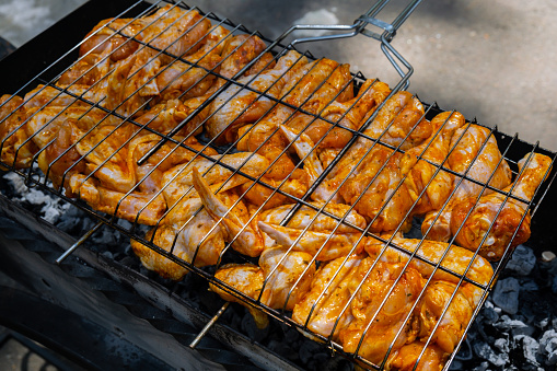 BBQ picnic time Roasted chicken legs and wings on grill. Grilling meat on outdoor grill grid tasty barbeque chicken steak with smoke flames juicy meat in the backyard in summer