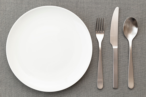 White plates and cutlery on the placemat.