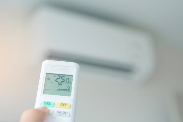 istock hand operating remote controller for adjust Air conditioner inside the room of office or house 2100733556