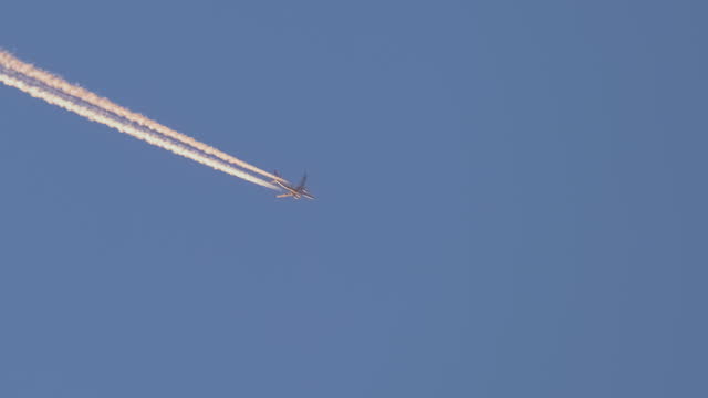 Passenger jet plane flying on high altitude on clear blue sky leaving white smoke trace of contrail behind. Air transportation concept