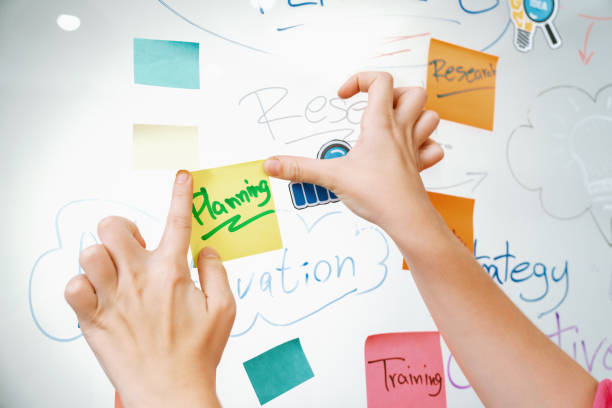 Closeup of professional businesswoman hand put and stick the colorful sticky notes on whiteboard while presenting business plan. Creative business meeting and brainstorming concept. Immaculate.