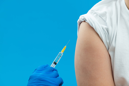 Doctor vaccinating for a boy on blue background.