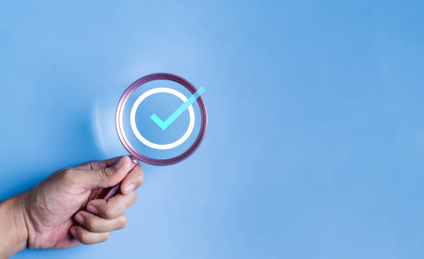 istock hand holding magnifier enlarging correct check mark icon and voting, approval, contract assignment. 2100815334