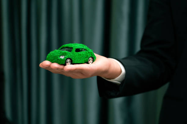istock Businessman holding green eco car model. Quaint 2100815424