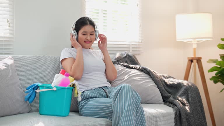 An Asian young homemaker is listening to music to relax and prepare for cleaning the house