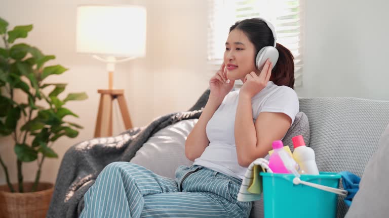 An Asian young homemaker is listening to music to relax and prepare for cleaning the house