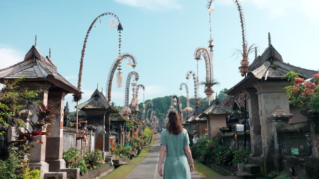 Female traveler walks on Balinese village street during Galungan and Kuningan celebrations