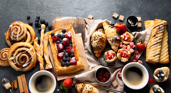 Different tasty freshly baked pastries on dark background. Top view. Copy space.