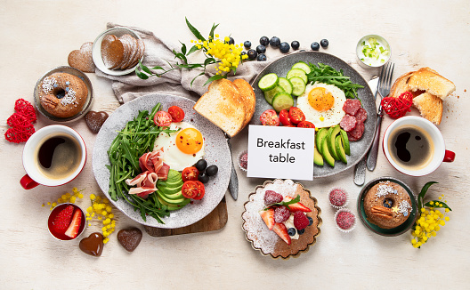 Breakfast served with coffee, fresh bakery, eggs, salad, meat and fruits. Holiday concept. Top view.