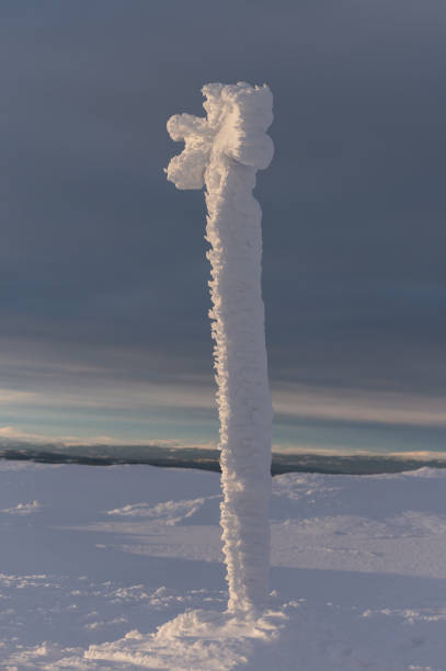 Golden sunrise light hitting a cross trail marker which is coated in thick ice in Scandinavia