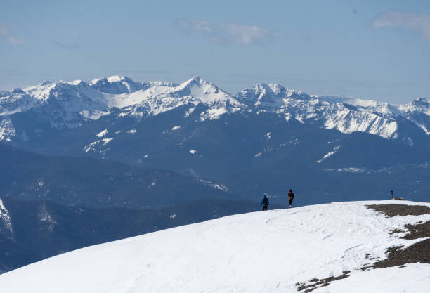 Two hikes descending from the summit of a mountain in the Bridger Range near Bozeman, with the Gallatin range in the background