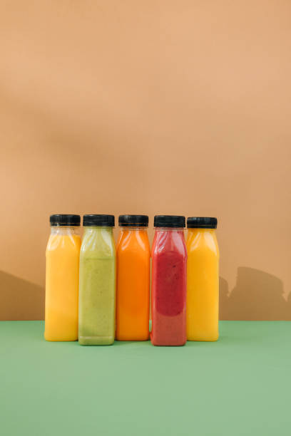 istock Fruit and vegetable smoothies in transparent plastic bottles. Red, green, orange smoothies on a brown-green background 2100929840