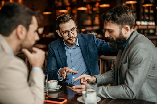 Small group of businessmen enjoy coffee and dialogue in a bar ambiance