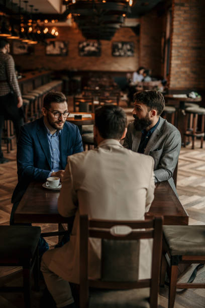 istock Corporate professionals networking over coffee, seated at a bar table 2100979304