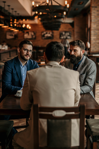 Businessmen gathered around the bar table, enjoying coffee and conversation