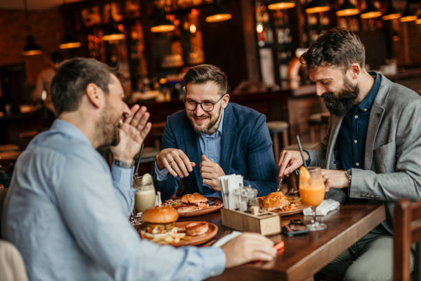 istock Three men in suits dining on burgers in a classy restaurant 2100981875