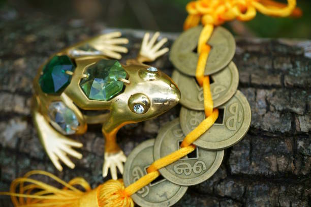 A frog figurine decorated with glass and a bunch of Chinese coins. Feng shui amulet. Attracting good luck.