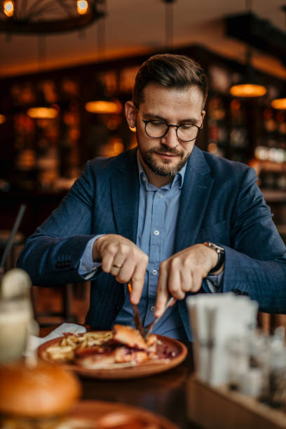 istock A businessman in formal wear enjoying a burger and conversation 2100986556