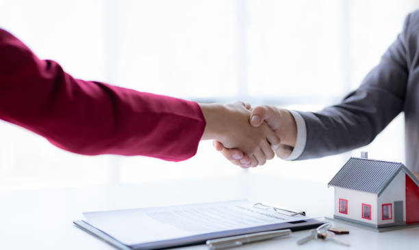 istock Real estate agent shakes hands with a client to sign a home purchase contract congratulating the client on the purchase. 2101021745