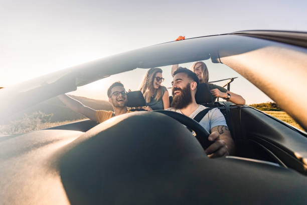 istock Carefree couples having fun on road trip in convertible car. 2101029154