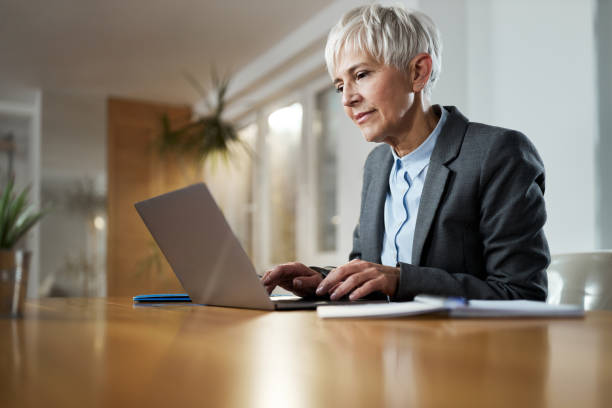 istock Smiling mature entrepreneur typing an e-mail on a computer at home office. 2101033875