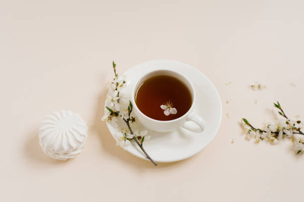 istock Tea cup standing with apple flowers and marshmallow on beige background 2101051456