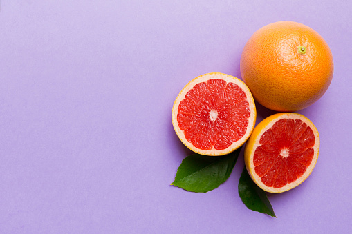 fresh Fruit grapefruit with Juicy grapefruit slices on colored background. Top view. Copy Space. creative summer concept. Half of citrus in minimal flat lay with copy space.