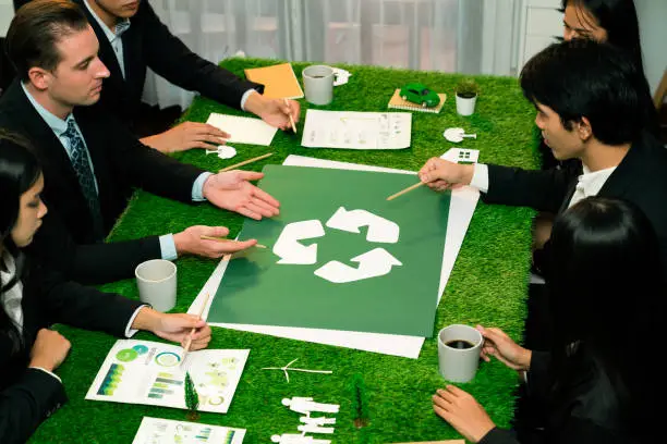 Photo of Recycle icon on meeting table with business people. Quaint
