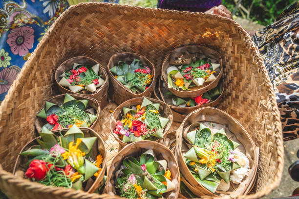 Balinese offerings, flower petals, rice and incense in bamboo leaf baskets, Hinduism.