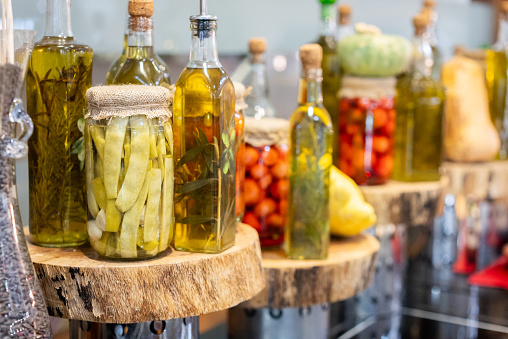 Various pickle jars and bottles of organic olive oil standing on the shelf