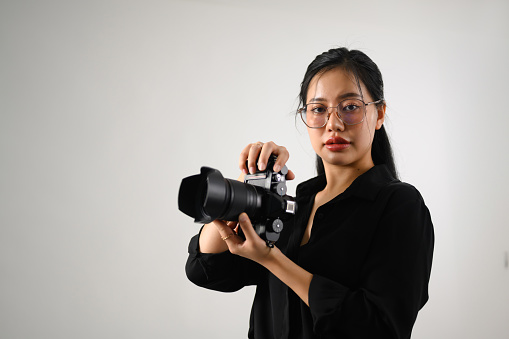 Beautiful female photographer with a dslr camera working at her studio.