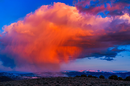 Dramatic Colorful Storm Cloud and Mountain Landscape Scenic - Snowcapped mountains with colorful pink and orange storm clouds as verga and rain fall and lit with warm sunset light. Sawatch Mountain Range, Colorado USA.