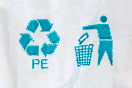 Recycling symbol made from plastic bottles on light green background.