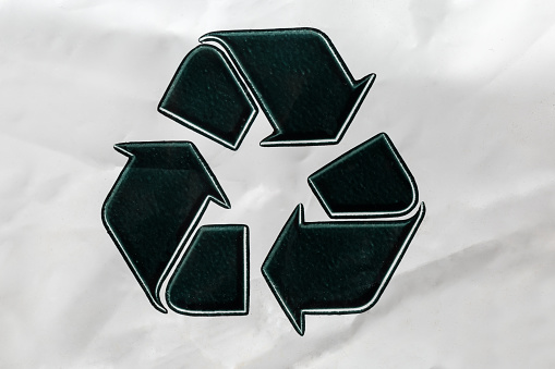 Pile of discarded plastic bottles in recycling symbol - on white background
