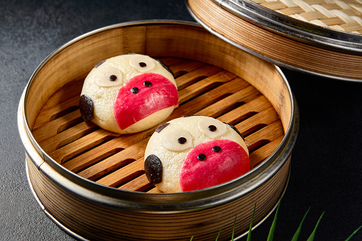 Cow-shaped bao buns in a traditional bamboo steamer; a whimsical twist on a classic Asian snack.
