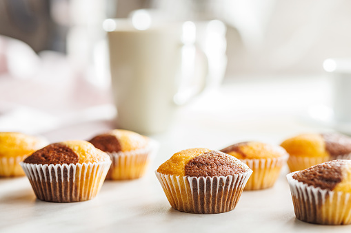 A variety of golden-brown muffins on a white table, inviting a taste.