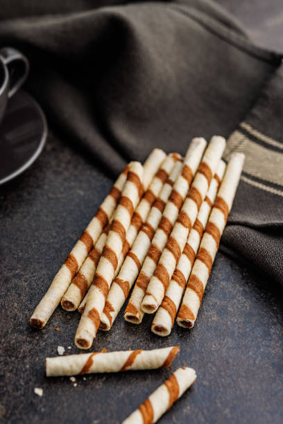 istock Delicious Striped Wafer Rolls on dark table. 2101211121