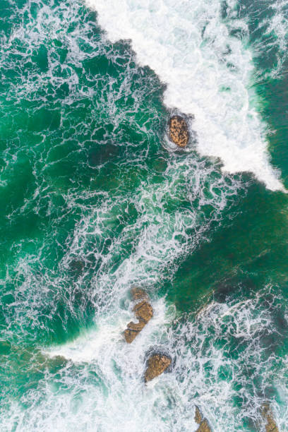 istock Aerial top down view on waves crash and splash on rocks. Waves crashing on rocky coast 2101224549