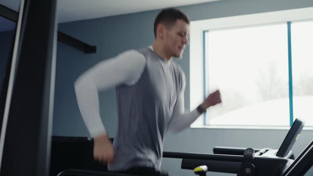 Active man with athletic body has training and run on treadmill in fitness club