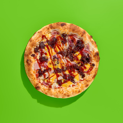 Meaty American pizza with thick crust, featuring sausage, bacon, and marbled beef on a bright green minimalist background. Top view, perfect for modern food photography, takeout, or casual dining. Square frame.