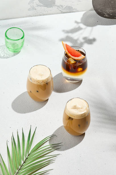 istock Assorted iced coffee on white concrete background with palm shadows. Minimal composition with cold summer drinks: espresso tonic, ice moccachino and latte. Summer composition for coffee menu. 2101244001