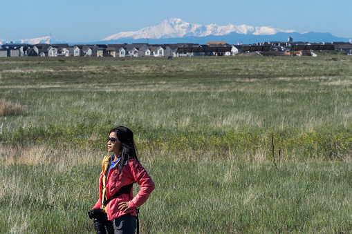 Woman standing in Rocky Mountain Arsenal National Wildlife Refuge with view of the view of Long Peak in the background