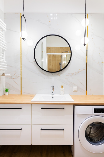 White modern bathroom vanity with washing machine and mirror.