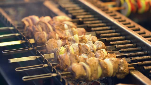 Juicy delicious barbecue is fried on hot coals on the grill. It rotates on a spit around its axis. Food festival Fried juicy meat on skewers. Pork meat is fried on coals.