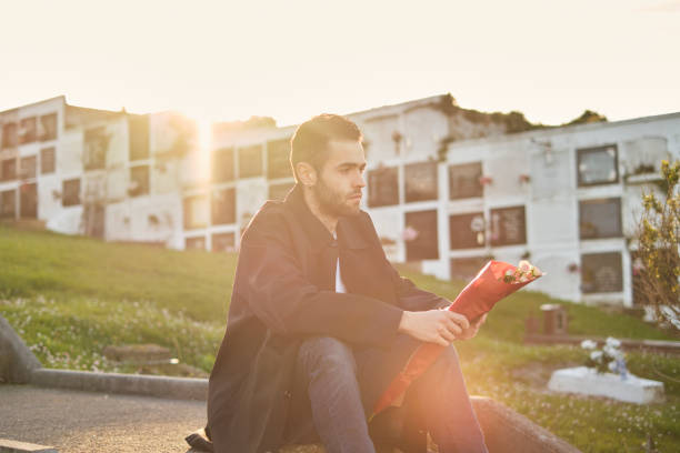 Single mature woman is sitting on park bench and looking for something in her backpack