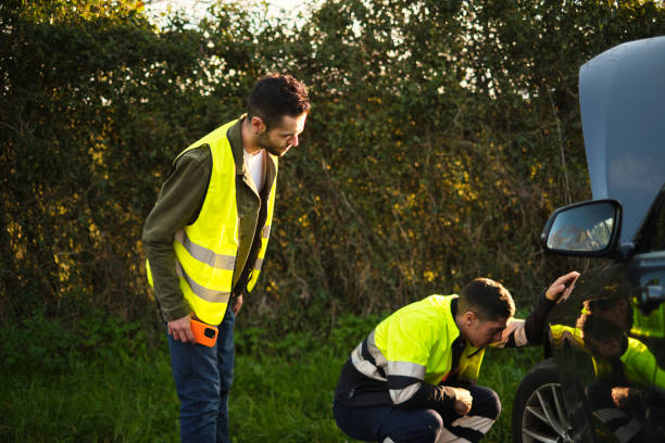 istock Service worker helping a man with a broken car on the road 2101283240